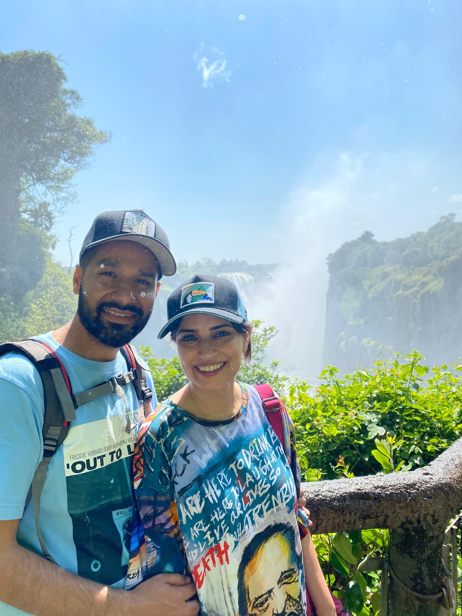 Victoria Falls doing its thing in the background — full spray, full rainbow, full soaking.